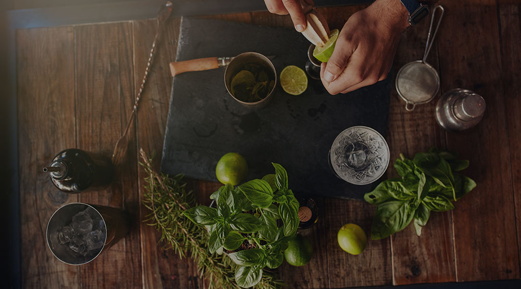 birds eye view of man making cocktails with fresh herbs