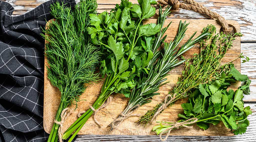 Bunches of herbs on a wooden chopping board - we provide bespoke service to our wholesale and retail customers